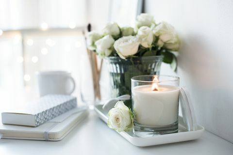 Valkoinen huoneen sisustus, palava käsintehty kynttilä ja kukkakimppu