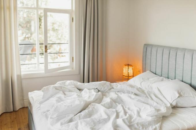 gulta viesnīcas istabā ar saburzītu segu, kas pamodina ceļojumu un brīvdienas