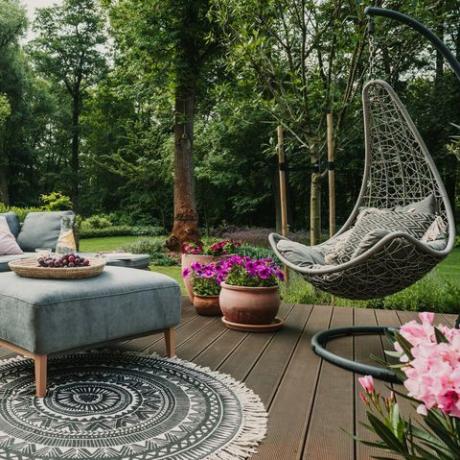 садовий дворик, прикрашений скандинавським плетеним диваном та журнальним столиком