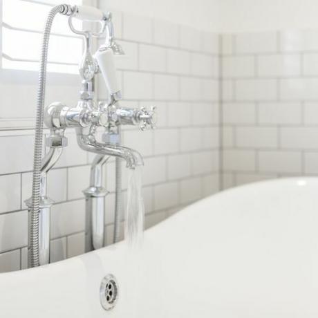 L'acqua che scorre dal rubinetto del bagno nella vasca da bagno bianca