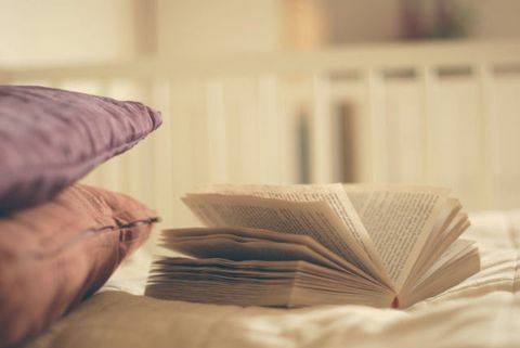 Sebuah buku terbuka dan dua bantal di tempat tidur