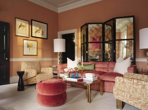 oranžiniai tapetai, raudona sofa, žalia pagalvėlė, raudona osmanė