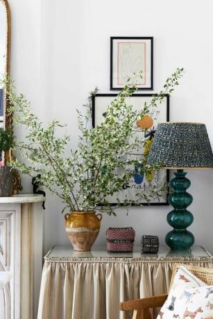 šoninis staliukas, žalia lempa, ruda vaza, sienų menas