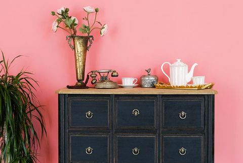 sena komoda su daiktais rožinės sienos fone yra gėlė puode, gražus interjeras vintažinio stiliaus