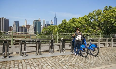 Moteris važiuoja dviračiu priešais Manheteno panoramą Niujorke