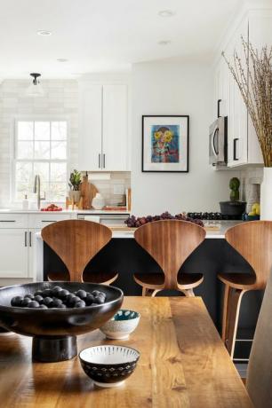 dřevěný jídelní stůl, kolekce mís, dřevěné barové stoličky, bílé kuchyňské skříňky