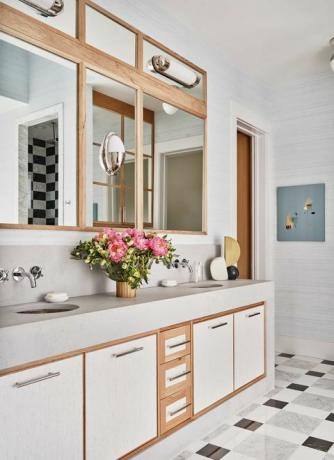 hvit servant på badet, håndtak i rustfritt stål, speil, blomster