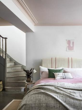Treppe, die ins Schlafzimmer mit rosafarbener Decke führt