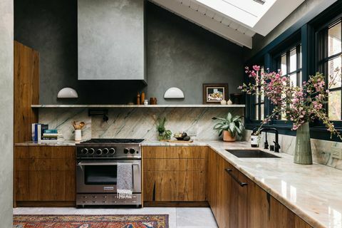 virtuvė su medinėmis spintelėmis, žalia langų apdaila, marmuriniais stalviršiais ir backsplash,