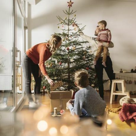 neljän hengen perhe koristaa joulukuusi