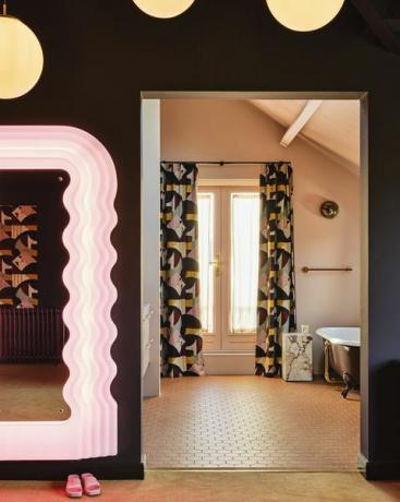 bagno privato tende abbinate, una porta aperta e una combinazione di colori tenui caramello collegano le due stanze specchio vintage piastrelle ettore sottsass winckelmans