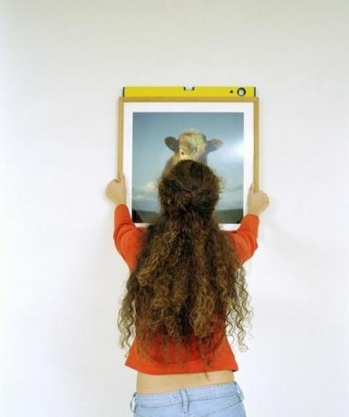 Mujer colgando una imagen con un nivel de burbuja