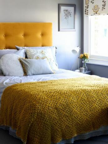 el armazón de la cama y la cabecera grandes crean una característica sorprendente en un dormitorio pequeño
