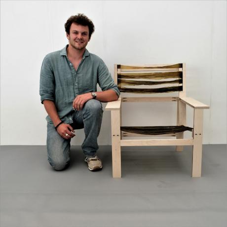 Portrét mladého návrháře nábytku krčícího se u židle z akce Green grads 2023