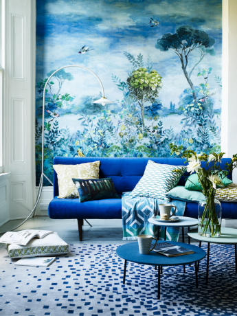 नीले मखमली सोफे और दीवार भित्ति के साथ रहने का कमरा