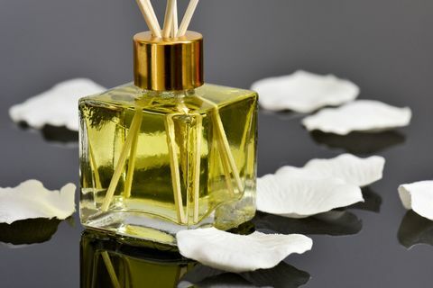Osvježivač zraka s mirisom trske s mirisom vanilije i latice ruže na reflektirajućoj površini.