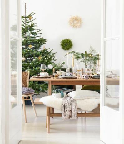 لقطة تغطية ، طاولة طعام خشبية مع شجرة عيد الميلاد في زاوية الغرفة