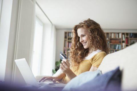 אישה מחייכת בבית עושה קניות באינטרנט