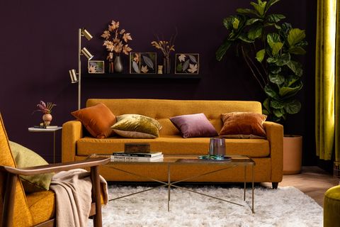 hořčicová pohovka ve fialových sametových polštářích v obývacím pokoji