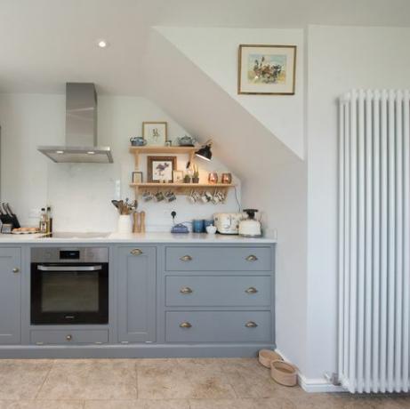 una vista general del interior de una cocina estilo shaker con gabinetes empotrados grises, unidades dentro de una casa
