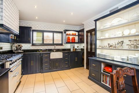 donkerblauwe en witte keuken met butlerspoelbak en dubbele kookplaat