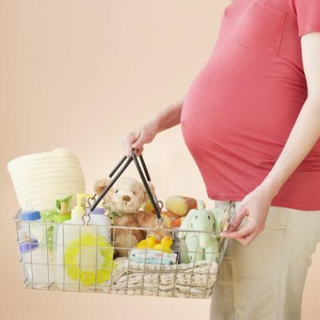 Studioaufnahme einer Frau mit einem Einkaufskorb voller Babyartikel, Mittelteil