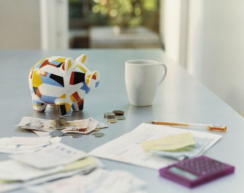 Piggybank, brit valuta, számológép, bevételek és egy bögre az asztalon