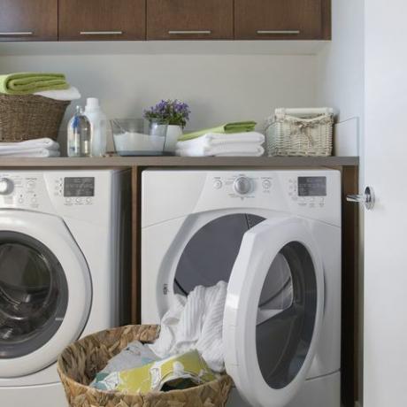 Suvremena praonica rublja s košarom čiste odjeće.