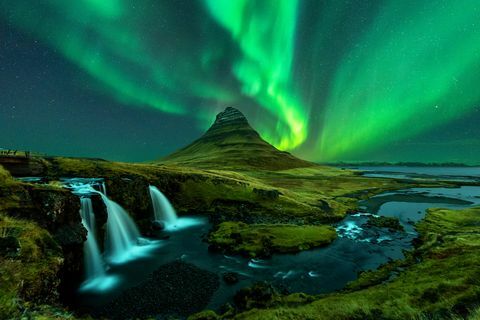 Nordlichter erscheinen über dem Berg Kirkjufell mit dem Wasserfall Kirkjufellfoss in Island.