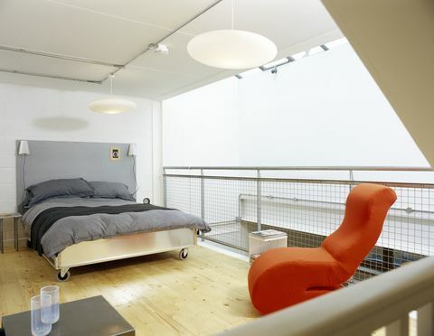 Kamar tidur modern dengan selimut abu-abu dan kursi oranye terang