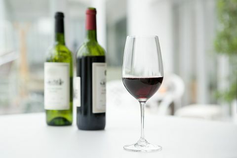 Rode wijn in flessen en glas op witte tafel