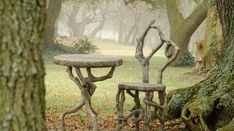 изображение на изкуствен буа стол и маса, поставени сред дървета в мъглив ден