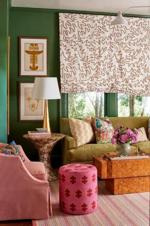 Grüne Wand, rosa Hocker, buntes Wohnzimmer
