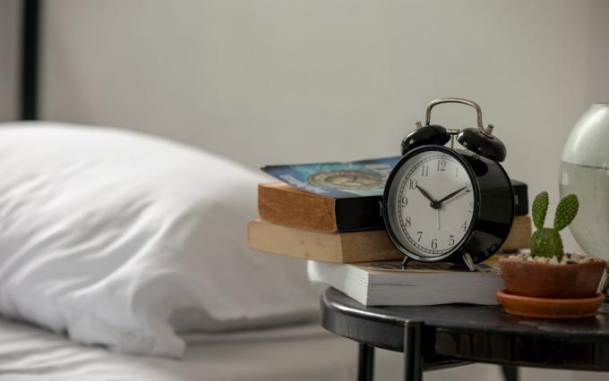 Närbild av väckarklocka vid sängen på bordet hemma
