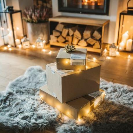gemütliches Wohnzimmer Winter Interieur mit Kamin, online bestellte und gelieferte Geschenke warten vor dem Kamin