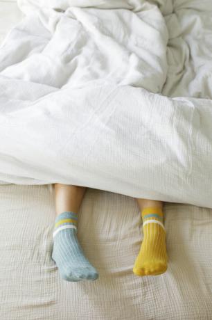 mulher vestindo meias azuis e amarelas na cama