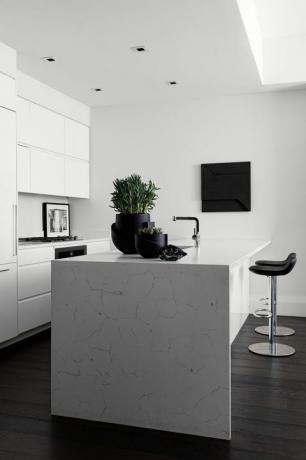 キッチン、白い大理石のカウンタートップの白いキャビネット、黒いバースツール