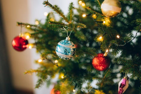 un petit sapin de noël dans un pot, décoré de boules, de guirlandes