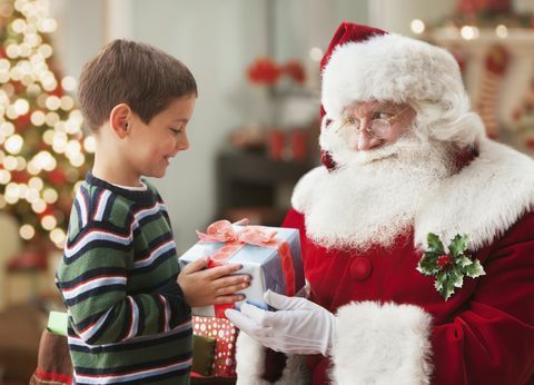 Weihnachtsmann gibt kaukasischen Jungen Weihnachtsgeschenk
