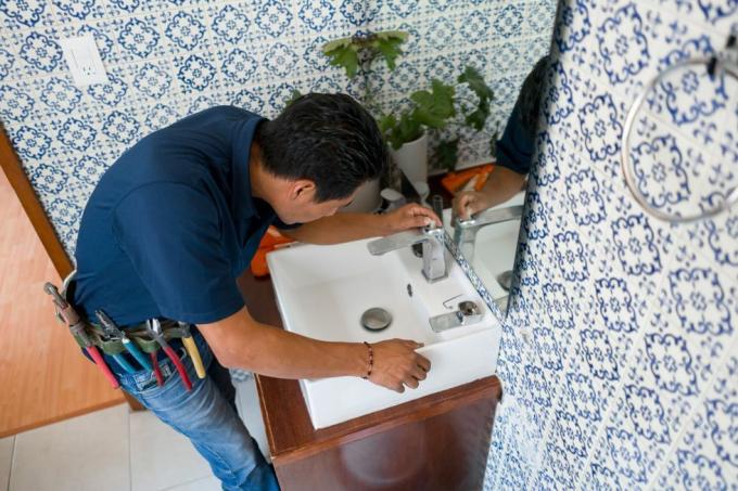 Klempner installiert einen Wasserhahn im Waschbecken eines Badezimmers