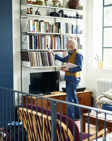 Homem sênior examinando sua coleção de discos na sala de estar