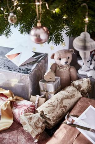 Nahaufnahme von Geschenken unter einem Weihnachtsbaum ein kleiner Teddybär und Silber und Gold verpackt PräsenteKostbare Geschenkeverleihen Geschenkverpackungen einen Hauch von Glamour durch die Verwendung vonPapieren in Silber, Kupfer und Marmor beendet