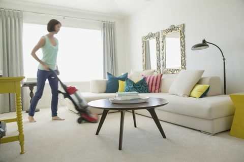 Женщина пылесосит свою современную гостиную