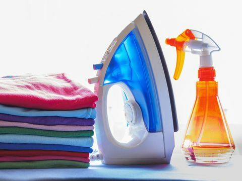 Žehlička, rozprašovač a hromada čistého prádla