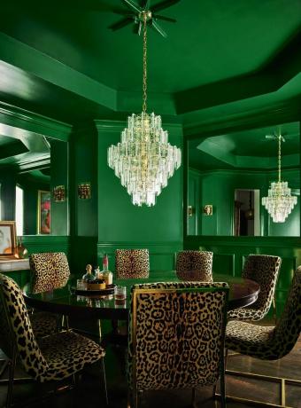 Hayvan desenli kumaştan sandalyelerle çevrili, yuvarlak masalı yeşil bir yemek odası