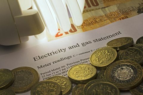 Elektricitets- og gasopgørelse med energibesparende pære og britiske pund sedler og mønter.