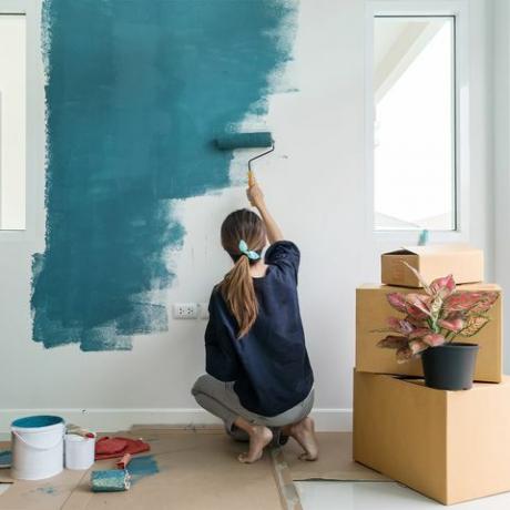 Frau malt eine Wand blau