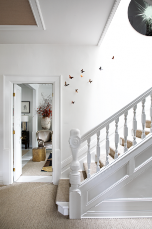 habitación blanca con esculturas de mariposas subiendo la escalera