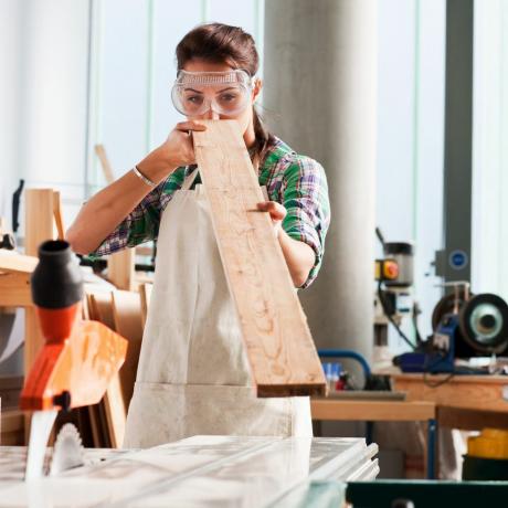 charpentier féminin vérifiant l'angle du bois dans l'atelier