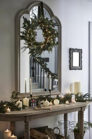 julkorsdekorationer med krans ovanför spegeln och ljus på konsolbordet